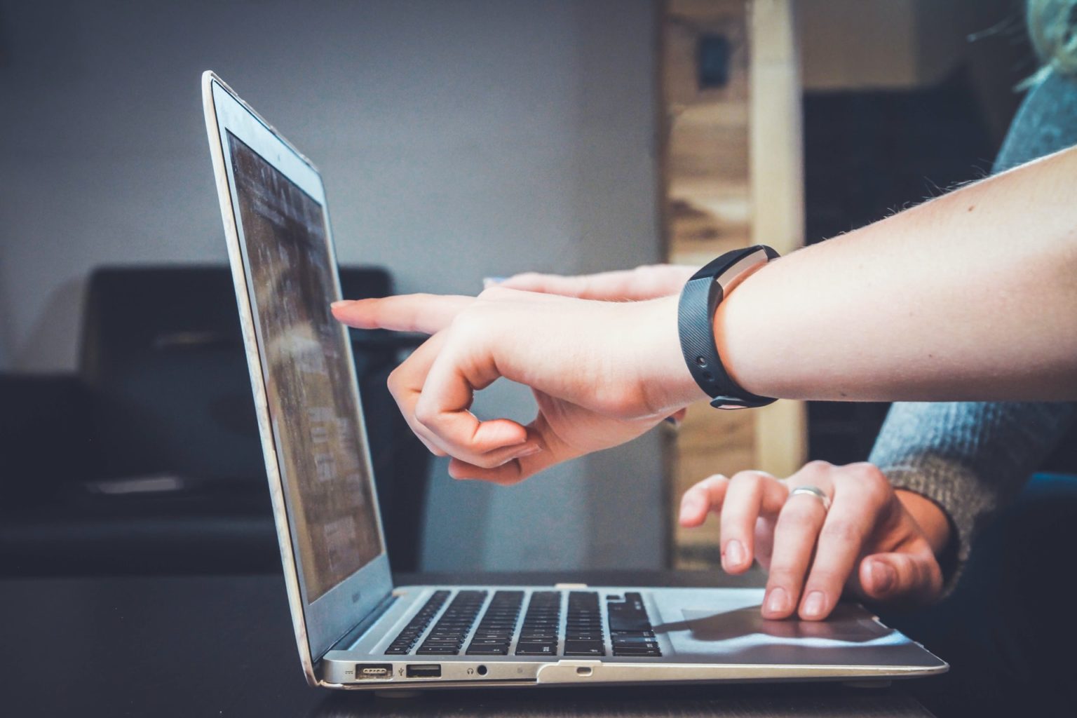 Two people pointing at a laptop screen while working together